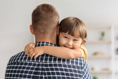 Babamı çok seviyorum. Babasını kucaklayan ve kameraya gülümseyen mutlu küçük çocuğun yakın portresi.