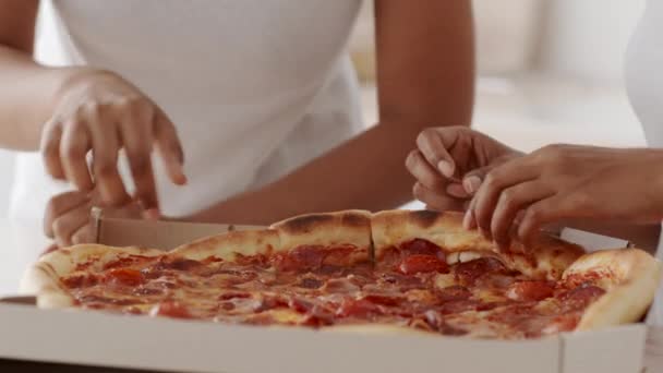 Manos de dos hembras negras tomando rebanadas de pizza de la caja en la mesa — Vídeos de Stock