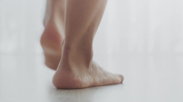 Primer plano de la joven mujer descalza irreconocible que va en el suelo blanco en casa, cámara lenta, espacio libre — Vídeos de Stock