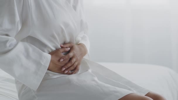 Buikpijn. Onherkenbare Afrikaans-Amerikaanse vrouw draagt witte badjas die lijdt aan buikpijn, lege ruimte — Stockvideo