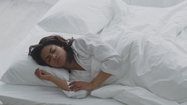 Problemas de sono. Jovem mulher afro-americana descontente rolando na cama desconfortável, sentindo-se irritada — Vídeo de Stock