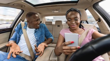 Zenci adam araba kullanırken karısına bağırıyor.