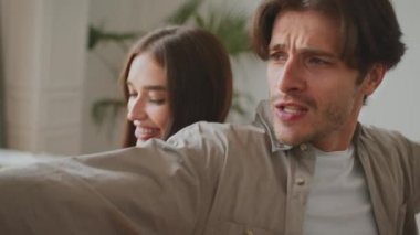 Mutlu ruh hali. Genç, pozitif çift yeni evinde dans ediyor, sırt sırta verip gülüyor.