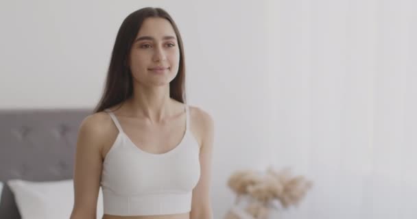 Jonge zelfverzekerde vrouw gaat naar huis interieur en glimlachen, bewegen langs de slaapkamer thuis interieur, tracking shot — Stockvideo