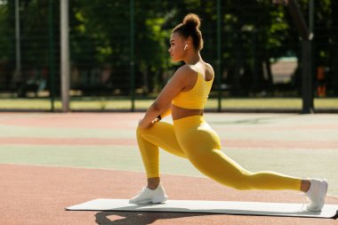 Genç siyahi kadın paspasın üzerinde ileri doğru hamle yapıyor.