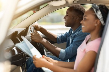 Neşeli siyahi kadın sürüş arkadaşına yardım ediyor, haritayı kontrol ediyor.