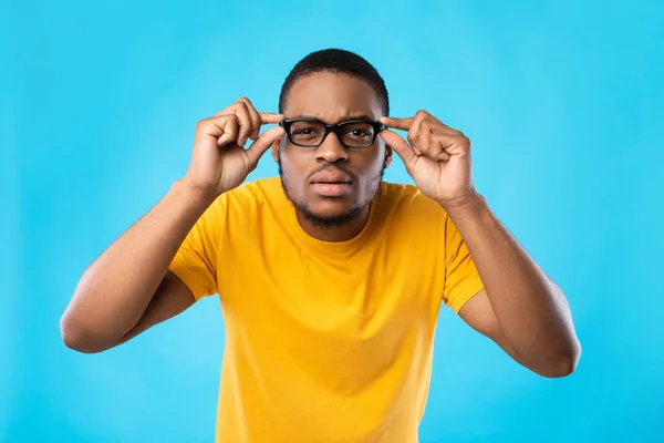 Schwarzer Kerl in Brille schielende Augen, die über blauem Hintergrund posieren — Stockfoto