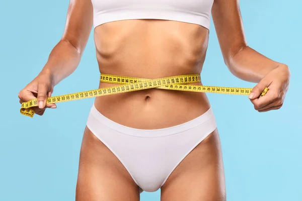 Primer plano de mujer irreconocible que mide la cintura con cinta — Foto de Stock