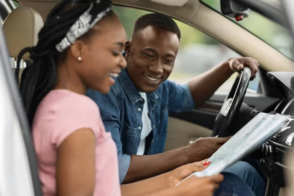 Mutlu siyah kadın erkek arkadaşının haritasını gösteriyor, arabada oturuyor. — Stok fotoğraf