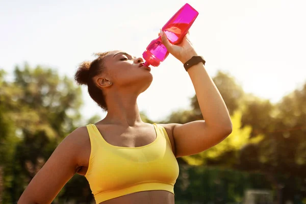 Fit black woman in yellow sportswear drinking water — Stock Photo, Image