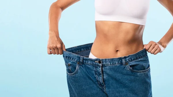 Nahaufnahme einer schlanken, fitten Frau, die große lose Jeans zieht — Stockfoto