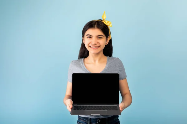 Funky indiana adolescente menina segurando laptop pc com tela em branco para o seu anúncio ou site no fundo do estúdio azul — Fotografia de Stock