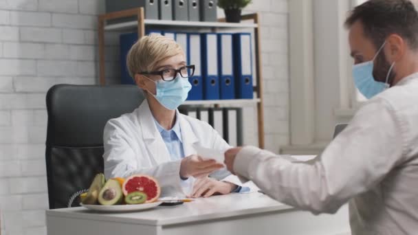 Na de revalidatie van het coronavirus. Dokter voedingsdeskundige geeft dieet plan om de patiënt voor immunisatie, zowel in het gezicht maskers — Stockvideo