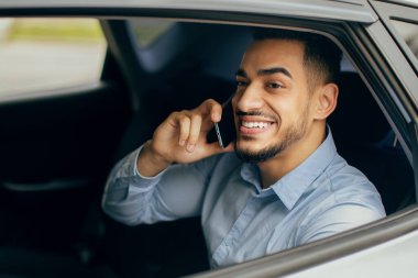 Neşeli bir orta doğu menajeri cep telefonuyla konuşuyor, arabada oturuyor.