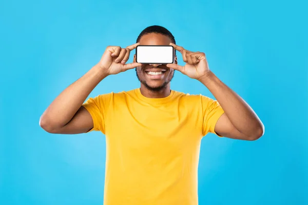 Zwarte man met telefoon voor ogen, blauwe achtergrond — Stockfoto
