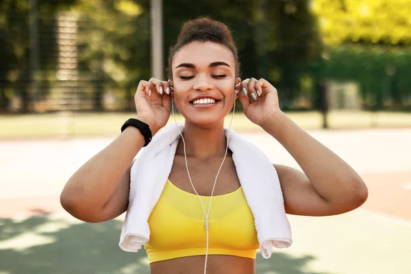 Deportiva mujer negra en ropa deportiva amarilla poniéndose auriculares — Foto de Stock