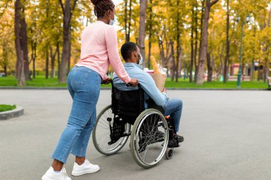 Tekerlekli sandalyedeki engelli genç adam elinde yiyecek dolu kağıt torba tutuyordu.