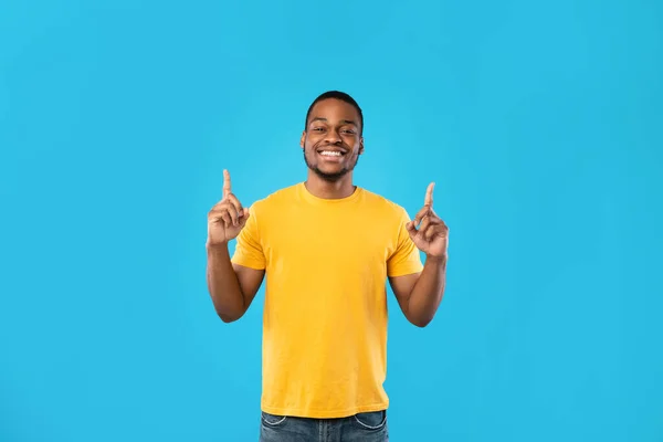 Afro-Amerikaanse man wijzende vingers naar boven glimlachen over blauwe achtergrond — Stockfoto