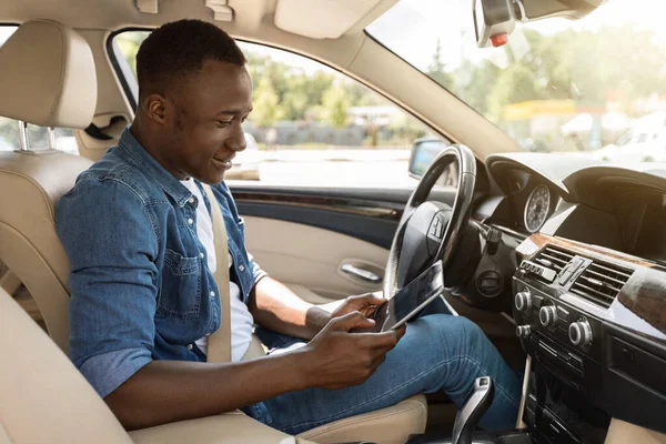 Positivo chico negro usando tableta digital durante la conducción de coches —  Fotos de Stock