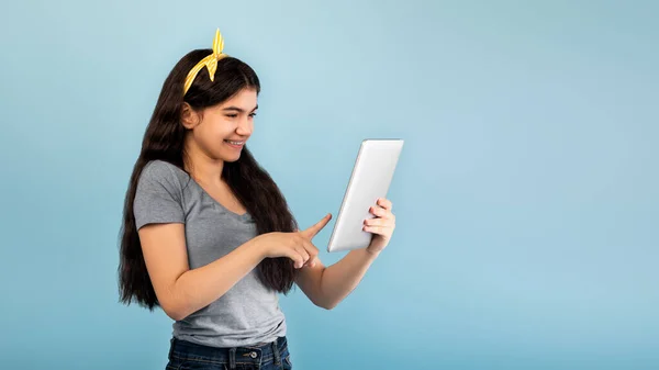 Portret van Indiase tiener meisje met behulp van tablet computer, online studeren op blauwe studio achtergrond, panorama met kopieerruimte — Stockfoto