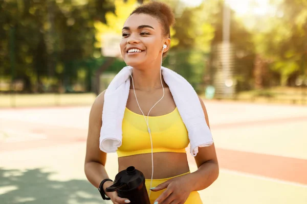 Mujer negra sonriente en ropa deportiva amarilla escuchando música — Foto de Stock