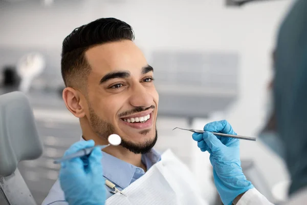 Nahaufnahme eines glücklichen männlichen Patienten aus dem Nahen Osten, der in einer modernen Klinik zahnärztlich behandelt wird — Stockfoto