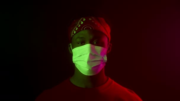 Μαύρος άντρας που βγάζει τη μάσκα προσώπου και ποζάρει στο σκοτεινό στούντιο — Αρχείο Βίντεο