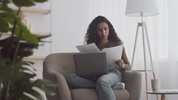 Jovem empreiteira independente comparando informações sobre documentos e laptop, encontrou erros e se sentindo desesperada — Vídeo de Stock