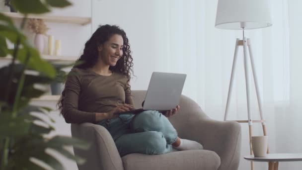 Online-Kommunikation. Junge fröhlich lockige Frau Videokonferenzen mit Familie, winkt mit der Hand zum Laptop — Stockvideo