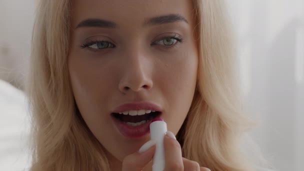 Lipverzorging. Mooie jonge blonde vrouw aanbrengen roze lippenstift thuis — Stockvideo