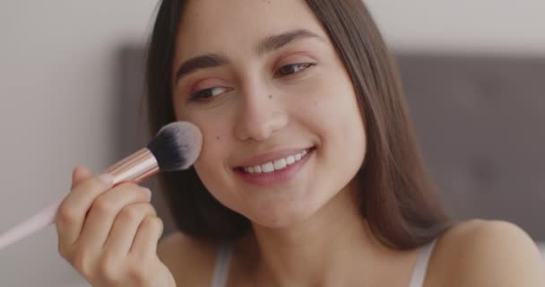 Närbild porträtt av söt Mellanöstern dam applicera rouge i ansiktet med make-up borste och ler mot sig själv — Stockvideo
