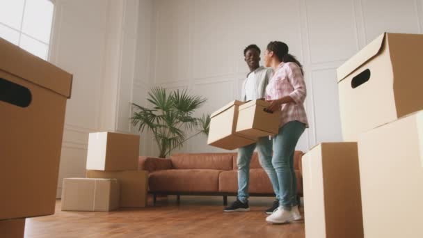 Ev taşıma konsepti. Genç, mutlu, evli, Afro-Amerikan çift kutuları odaya taşıyor ve kucaklaşıyorlar. — Stok video