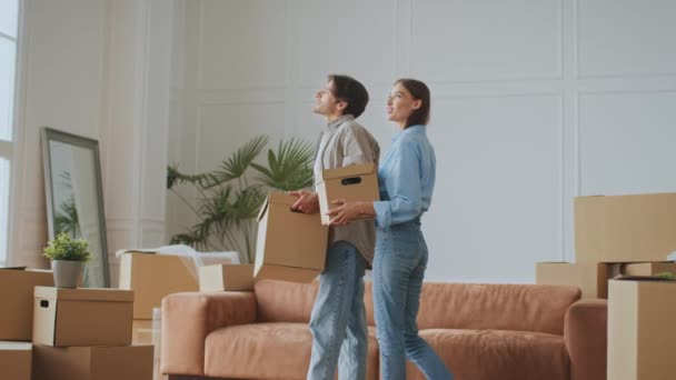 Día de mudanza. Feliz pareja joven en el amor que viene a la habitación con cajas de mudanza y discutir nuevo apartamento — Vídeo de stock