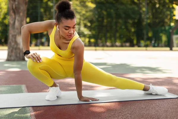 黄色のスポーツウェアストレッチ足の屋外で自信の黒人女性 — ストック写真