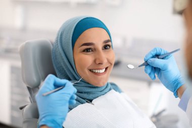 Klinikteki dişçiyle tesettürde gülümseyen müslüman kadın