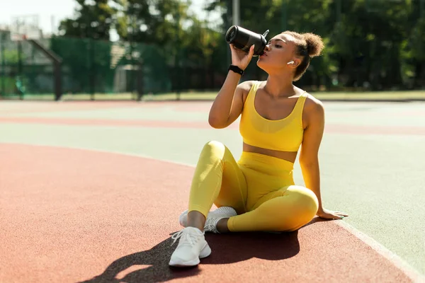 Retrato de mujer negra deportiva en agua potable de ropa deportiva amarilla — Foto de Stock