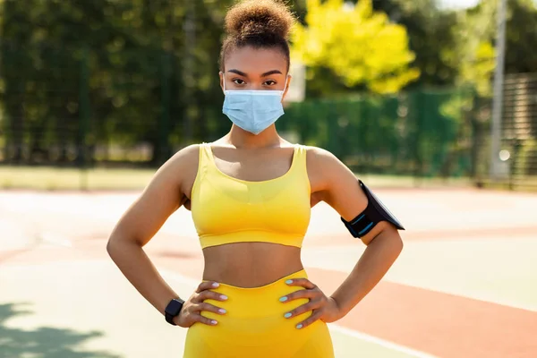 Woman wearing protective face mask and sportswear posing