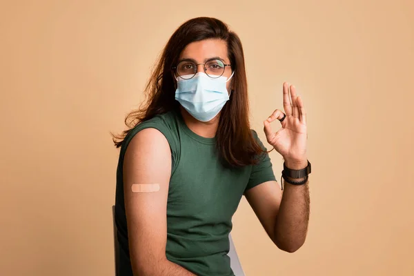 Man in face mask showing okay gesture, plaster on shoulder — Stock Photo, Image