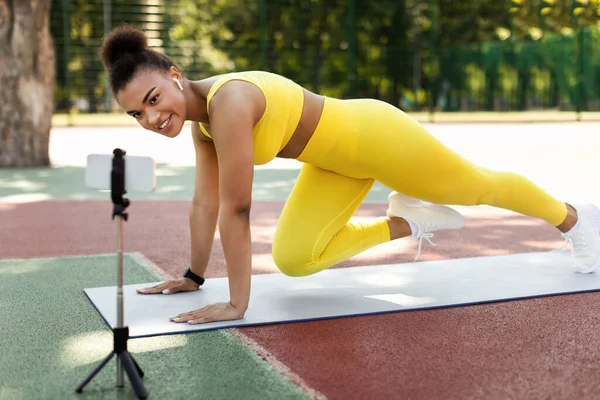 Mujer negra joven haciendo ejercicio delante de un smartphone — Foto de Stock