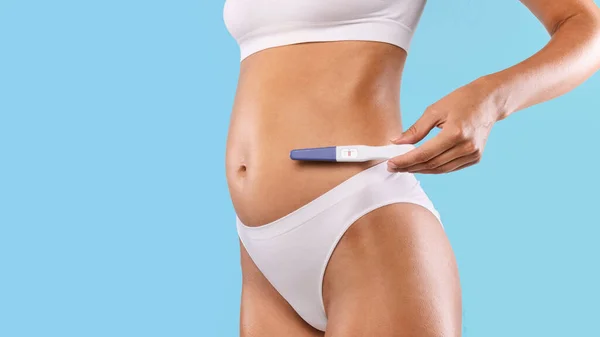 Frau hält Schwangerschaftstest in weißer Dessous ab — Stockfoto