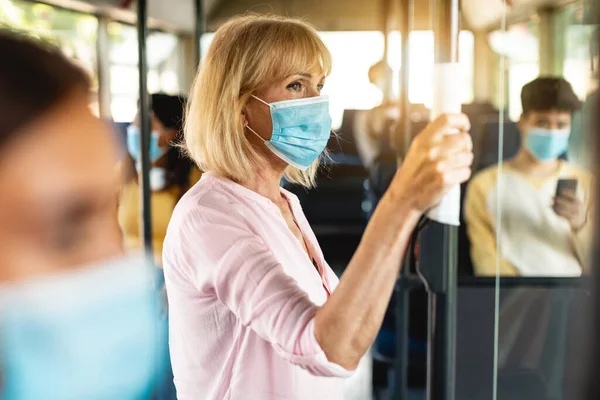 Focused mature woman wearing medical mask taking bus — Stock Photo, Image