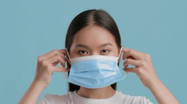 Asyalı Kadın Mavi Arkaplan Üzerine Koruyucu Yüz Maskesi Takıyor