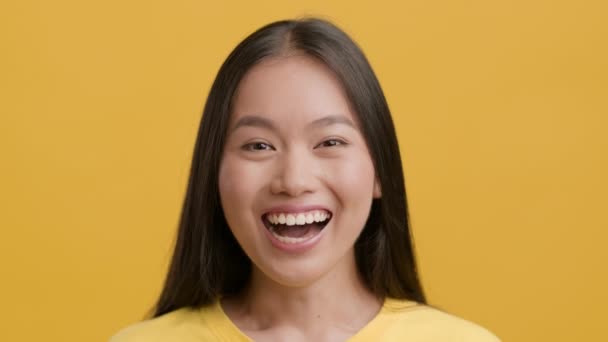 Retrato de la alegre mujer china sonriendo a la cámara, fondo amarillo — Vídeo de stock