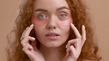 Kızıl Saçlı Kadın Bej Arkaplan Üzerine Göz Altında Yamalar Uyduruyor