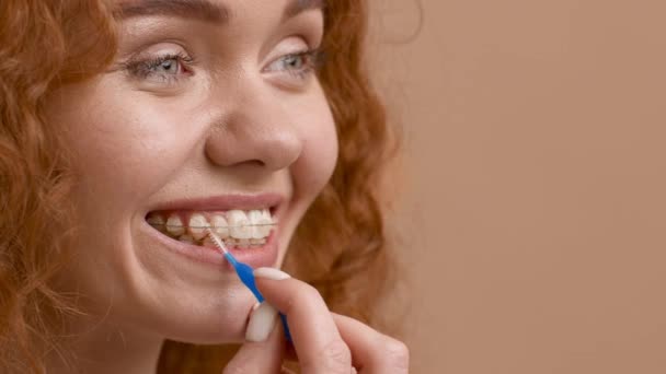 Mujer usando cepillo interdental limpieza de dientes con soportes, fondo beige — Vídeo de stock