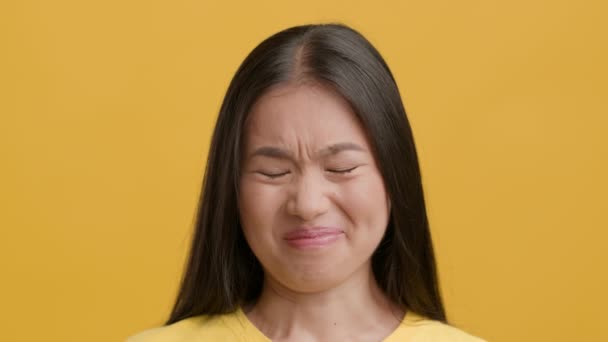 Äcklig asiatisk kvinna rynkar pannan dålig lukt över gul bakgrund — Stockvideo
