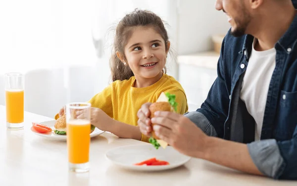 キッチンで父と一緒にサンドイッチを食べる幸せな小さなアラブの女の子の肖像画 — ストック写真