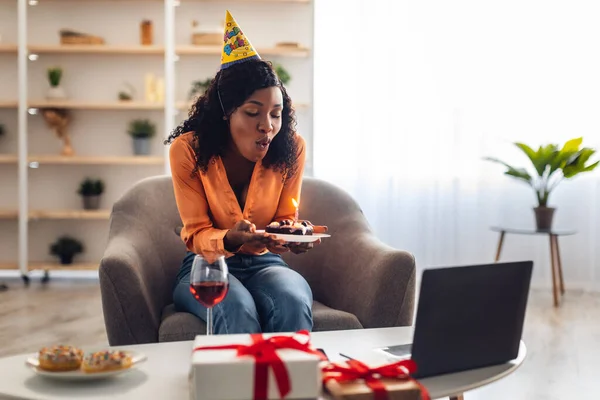 Zwart vrouw blazen kaars op taart met online verjaardag Indoor — Stockfoto