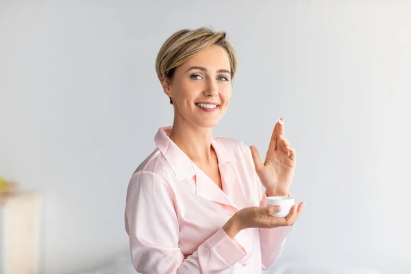 Primer plano de mujer sonriente sosteniendo tarro de crema — Foto de Stock