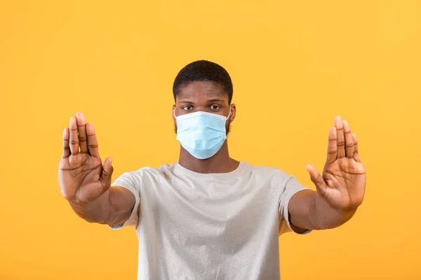 Afrikansk amerikan i ansiktsmask gester STOP till kamera, uttrycker negativitet mot coronavirus pandemi — Stockfoto